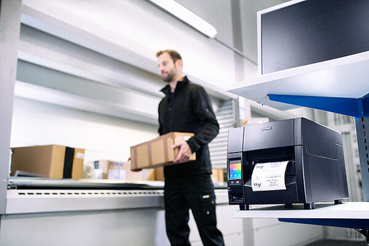 Citizen CL-S703III industrial label printer, black Hi-Open metal case, colour touch LCD, tear bar, 300 dpi, thermal transfer (CLS703IIINEXXX) – in use printing shipping labels in a warehouse